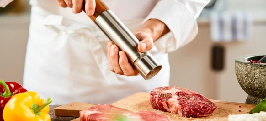 Ein Koch nutzt eine Pfeffermühle